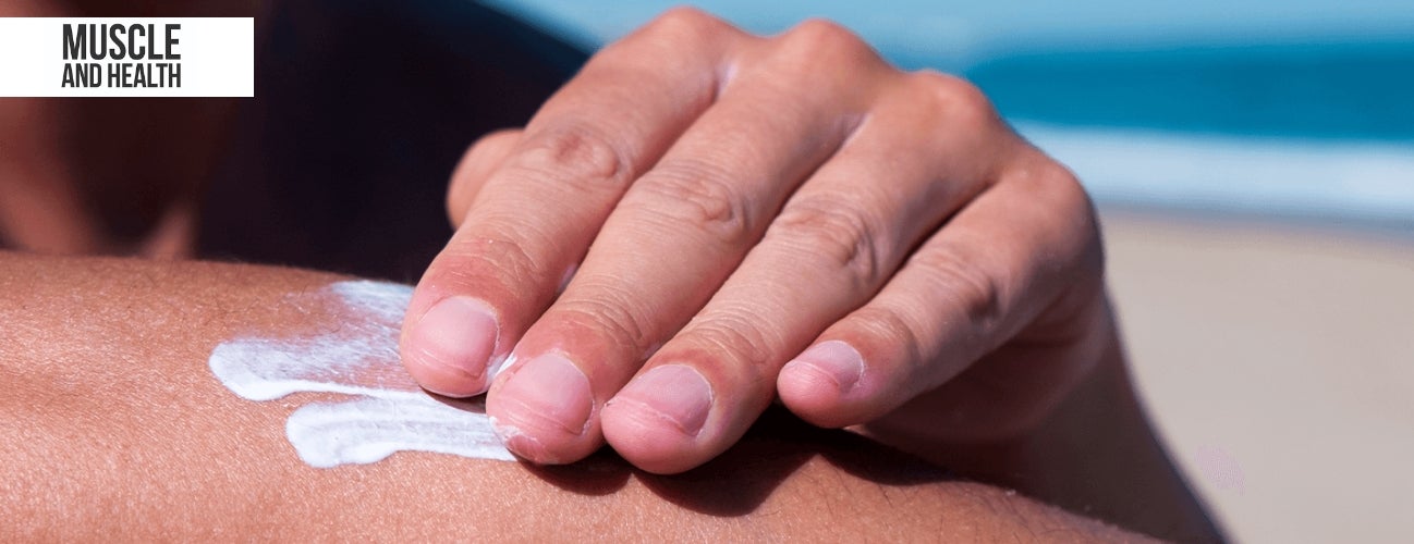 Image of someone applying sunscreen to their arm on the beach.