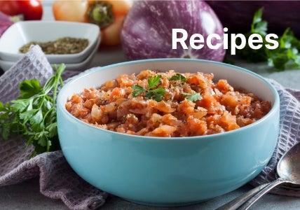 Recipes. A lifestyle shot of a salmon bowl with various vegetables behind it.