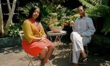 A still of two women speaking in a garden.