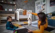 Parent playing with baby and dog in nursery