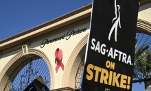 A black poster reading "SAG-AFTRA on strike!" outside the Paramount Pictures gate in Hollywood.