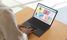 Woman's hand resting on a Microsoft Surface Laptop 3's trackpad, while she sits at a desk