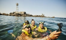 Four people snorkeling and taking selfie in ocean