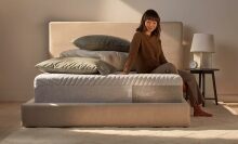 Woman sits on a Casper Sleep Wave Memory Foam mattress.