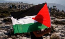 A Palestinian protester waves a Palestinian flag during a demonstration in the village of Ras Karkar west of Ramallah.