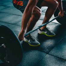 from legs down: person deadlifting against black mat