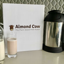 Almond cow milk maker next to glasses of non-dairy milk