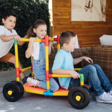 Three kids playing with the Omagles builder set outdoors.