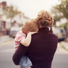 young boy resting on mother's shoulder while she holds him