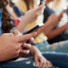 A row of children holding their cell phones. 