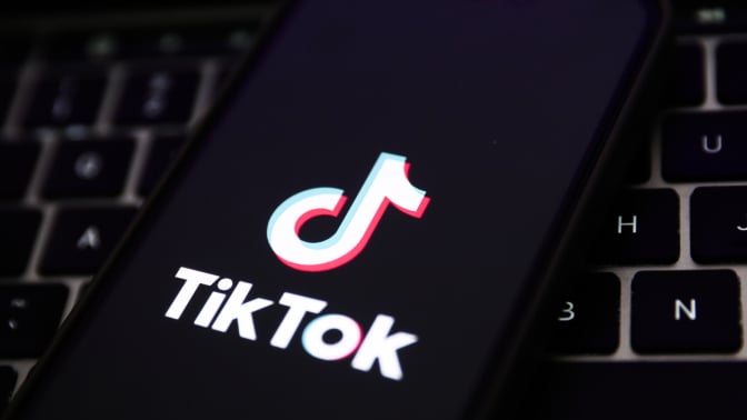 A laptop keyboard and TikTok logo displayed on a phone screen are seen in this illustration photo