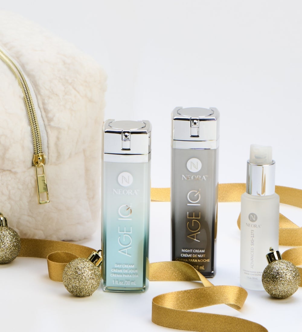 Free Gift! Bottles of Age IQ Night and Day Creams & Sig Serum are surrounded by a white bag, festive, gold ribbon and ornaments.
