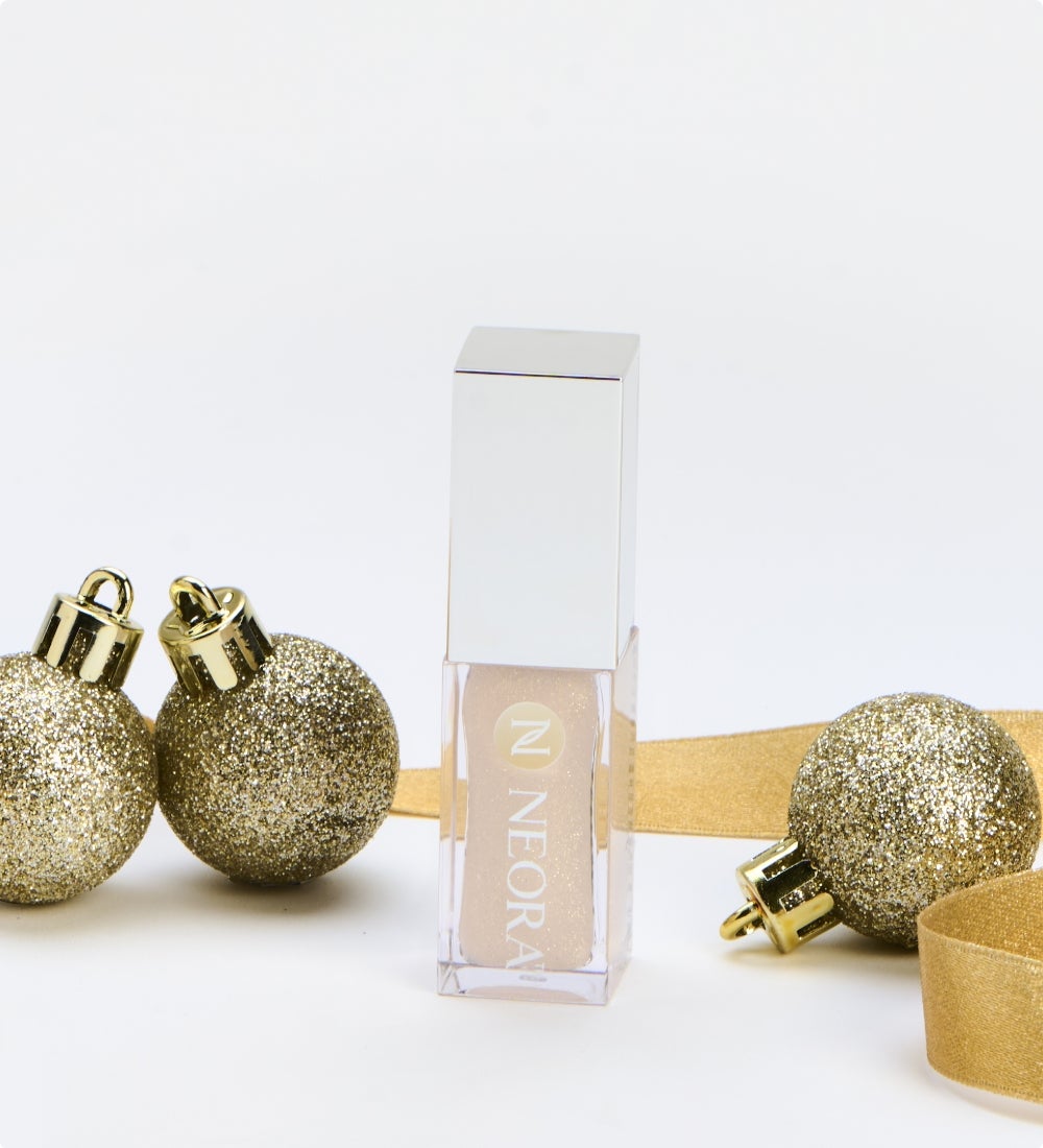 New! A Lip Oil Container is surrounded by festive, gold ribbon and ornaments.