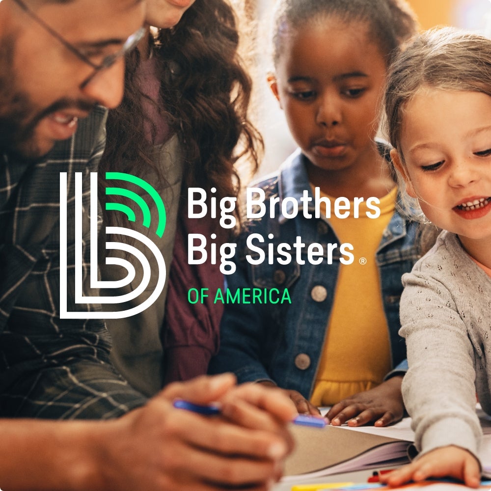 Two adults reading a document to two kids. Big Brothers Big Sisters of America is overlaid on top of the image.