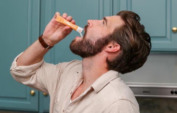 Lifestyle shot of a man taking NeoraFit™ Block + Balance Pre & Probiotic Powder.