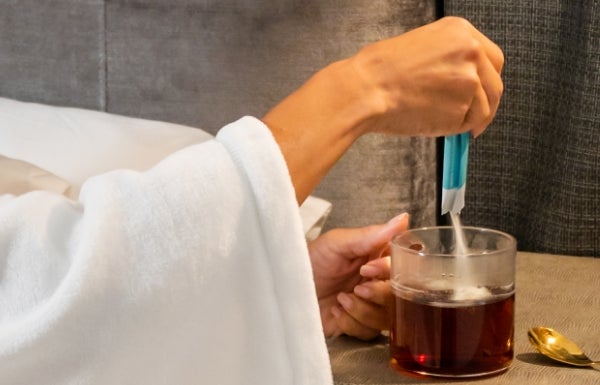 Lifestyle shot of NeoraFit Cleanse + Calm Nightly Gentle Cleanse Powder being poured into a glass cup.