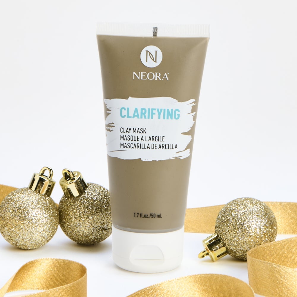 Neora’s Clarifying Clay Mask tube surrounded by gold ribbon and ornaments. 