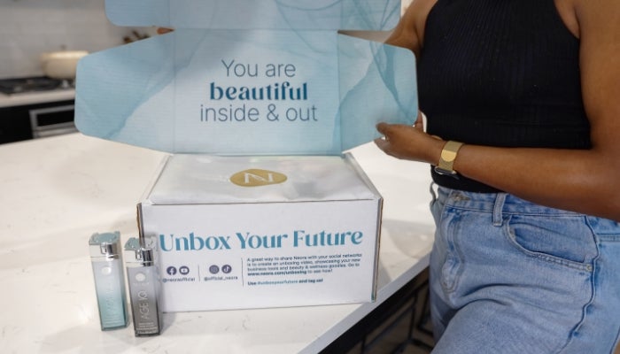 Image of woman next to the Neora Welcome Kit sitting on a kitchen island