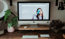 squarespace's website pulled up on an imac sitting on a wooden desk that's surrounded by plants