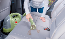 person vacuuming their car with portable vacuum 