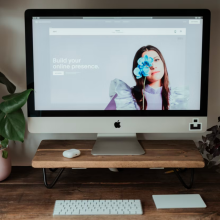 squarespace's website pulled up on an imac sitting on a wooden desk that's surrounded by plants