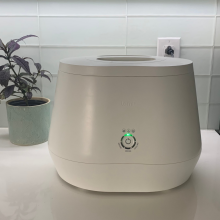 Lomi composter on kitchen counter with plant in the background