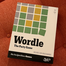 wordle board game box sitting on orange couch cushion