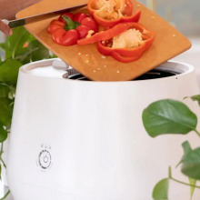 Person's hands scraping vegetables into Lomi composter