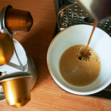 Morning cup of fragrant coffee from coffee machine on the wooden background with capsules holder