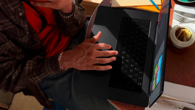 a top-down view of a man scrolling on the touchpad of an m3 pro apple macbook pro