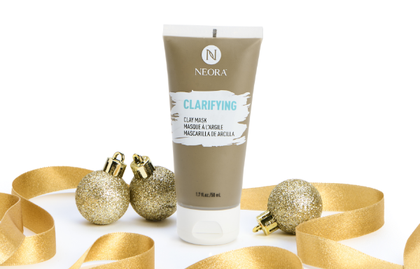 A tube of Neora’s Clarifying Clay Mask surrounded by gold ribbon and ornaments.