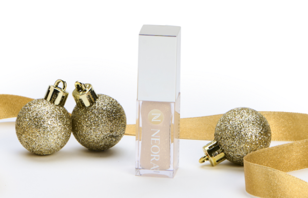 Neora’s Shimmer Lip Oil container surrounded by gold ribbon and ornaments. Accompanying text states “Holiday Exclusive.”